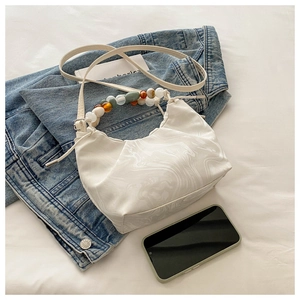 Close-up of marble pattern dumpling bag with colorful beaded handle on denim