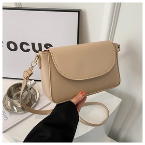 Detail of beige flap crossbody bag featuring a golden metal hook and leather strap