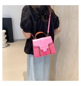 Sac à main rose effet crocodile porté par un mannequin dans un intérieur minimaliste