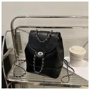Detail of black faux leather backpack with silver chain strap and metal turn-lock closure