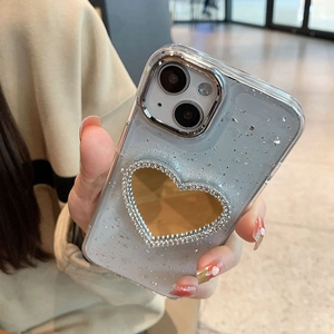 Detail of silver heart-shaped mirror on clear iPhone case with glitter and rhinestones
