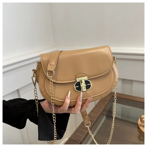 Detail of tan saddle bag with golden twist lock and chain strap in close-up shot