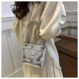 Close-up of a silver metallic crossbody bag featuring five 3D bows and a bead chain