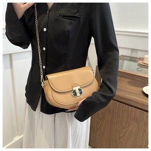Detail of tan saddle bag with golden chain strap and premium oval hardware lock