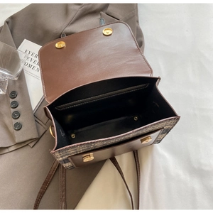 Detail of dual magnetic snap closure and textured weave on a brown crossbody bag