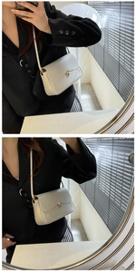 Detail of a creamy beige crossbody bag with elegant gold hardware lock and slim shoulder strap