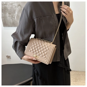 Detail of beige quilted shoulder bag with golden chain strap and rectangular twist lock