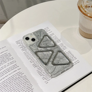 Détail de coque iPhone avec texture marbre gris et triangles en métal sur un livre