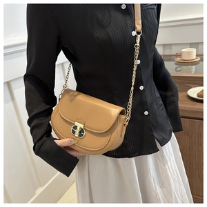 Detail of khaki saddle bag with stylish black and gold twist lock and chain strap