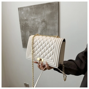 Close-up of beige quilted leather handbag with iconic metal clasp and chain strap