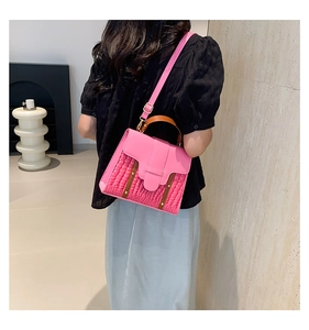 Detail of pink crocodile pattern texture and brown leather handle on fashion handbag