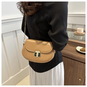 Close-up of caramel leather saddle bag featuring a T-shaped gold metal twist lock