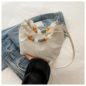 Detailed shot of marble pattern bucket bag with colorful beads on denim background