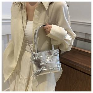 Detail of silver metallic mini bag with 3D bow accents and elegant beaded chain strap