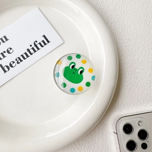 Vue détaillée du support de téléphone rond avec un mignon crapaud vert et des pois