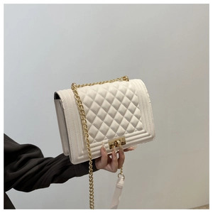 Detailed view of quilted faux leather texture and gold metal buckle on white flap bag