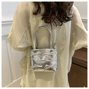 Detail of silver metallic handbag with five decorative bows and a delicate bead chain strap
