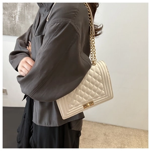 Close-up of white quilted chain bag with gold twist lock and elegant leather strap details