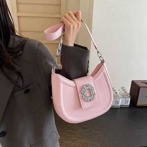 Pink half-moon saddle bag with rhinestone buckle and silver chain strap held by model