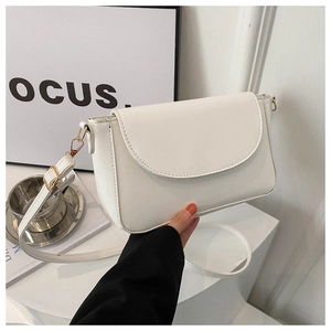 Detail of a white minimalist crossbody bag showing smooth texture and golden metal hooks