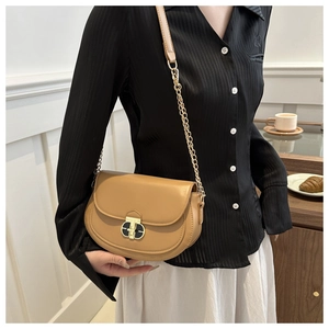 Detail of a brown leather saddle bag with gold metal chain and vintage lock buckle