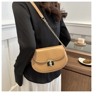 Detail of camel saddle bag with gold metal twist lock and chain strap on a model