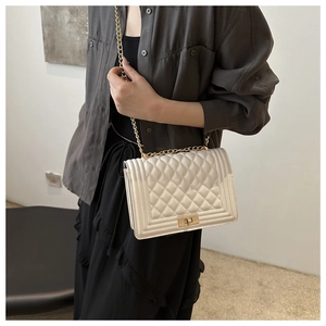 Model wearing a white quilted crossbody bag with gold chain strap and metal lock