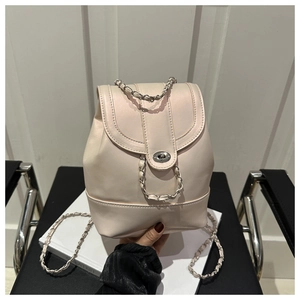 Close-up of cream mini backpack featuring silver twist lock and metal chain strap details