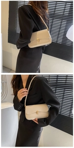 Detail of minimalist cream shoulder bag with golden buckle shown on a black suit blazer