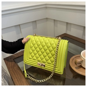 Detail of neon green quilted leather texture with gold metal chain and rectangular turn-lock