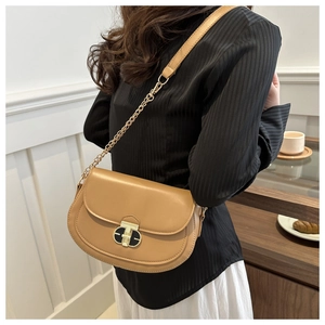 Detail of caramel saddle bag with gold T-shaped clasp and chain leather strap