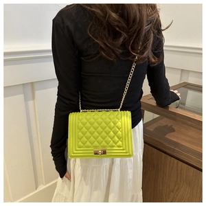 Detail of neon green quilted crossbody bag with golden chain strap on a white skirt