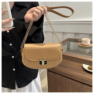 Detail of khaki saddle bag with golden clasp and chain strap in a cozy interior