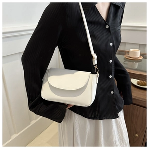 Minimalist white leather crossbody bag with adjustable strap worn on model side