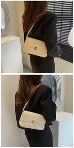 Detail view of a beige minimalist underarm bag with gold lock buckle and smooth leather