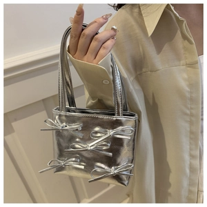 Silver mini handbag featuring five decorative bows and a metallic finish on a model side-view