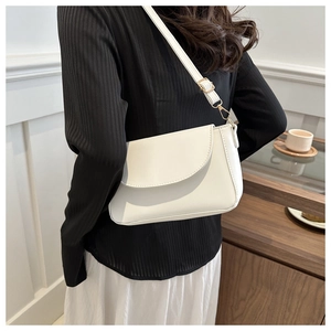 Detail of minimalist white leather crossbody bag with gold hardware on a shoulder strap