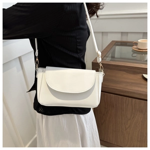 Close-up of a white leather crossbody bag showing fine stitching and gold metal hardware