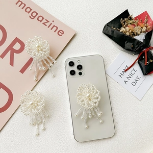 Elegant pearl flower phone grip with long tassels mounted on a white smartphone