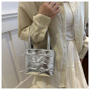 Detailed view of silver metallic mini handbag featuring five decorative 3D bows and handles