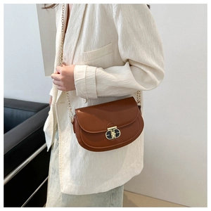 Brown semi-circle saddle bag with gold metal lock and chain strap shown on a model