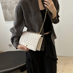 Elegant white quilted shoulder bag with gold chain strap shown on model in premium styling