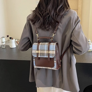 British style plaid backpack with brown leather trim shown in a cozy cafe setting