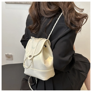 Detail of a creamy off-white backpack featuring woven chain straps and a metal twist lock