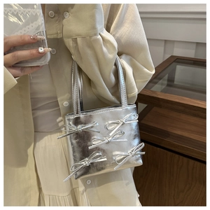 Detail of silver handbag featuring 3D bows and metallic texture in high-end finish