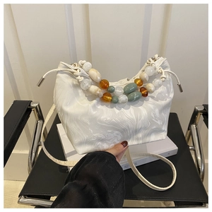 Detailed shot of white marble pattern bucket bag with colorful beaded handle on a chair