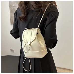 Close-up of cream white backpack with metal chain strap worn by a model