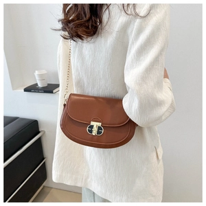 Close-up of brown saddle bag with lychee grain texture and gold chain strap