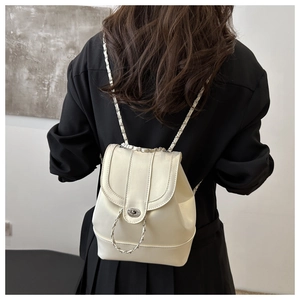 Detail view of a cream white minimalist backpack with chain straps and silver twist lock