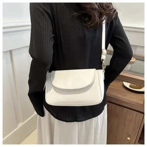 Side view of white leather crossbody square bag worn by a model in a natural setting